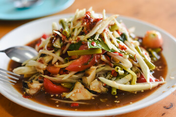 Thai dish called Som Tum, also known as papaya salad. It is made from finely shredded green papaya, mixed with green beans, tomatoes, and other fresh vegetables.
