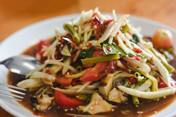Thai dish called Som Tum, also known as papaya salad. It is made from finely shredded green papaya, mixed with green beans, tomatoes, and other fresh vegetables.