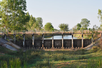 small dam or water control structure with a bridge on top. The dam appears to be constructed of concrete and features vertical supports, providing strength and stability.