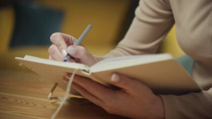 A person writes thoughtfully in a journal while seated in a warm, inviting space. The act of journaling offers a moment of reflection, creativity, and personal expression.