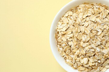Composition with oatmeal flakes on beige background. Cooking breakfast
