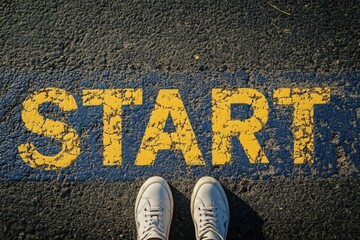 Start line on asphalt with worn yellow letters and a person wearing white sneakers standing in front of it, symbolizing new beginnings and opportunities