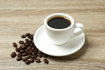 Cup of coffee and coffee beans on wooden background