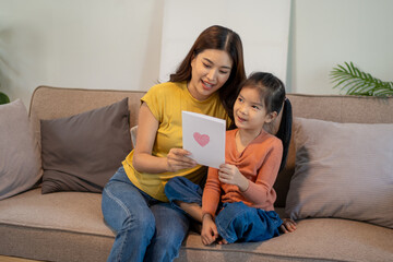 Lovely mom and little young daughter spending time together in their living room.