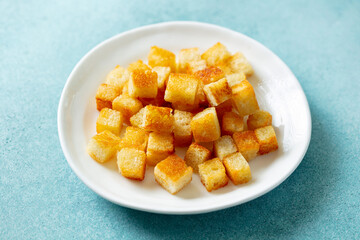 Croutons on a white plate. Blue background. Close up.
