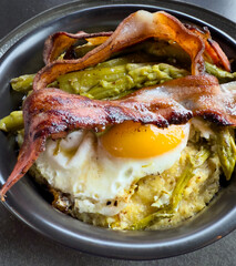 Traditional Italian dish. Polenta, eggs, asparagus and crispy bacon. Caloric and tasty dish