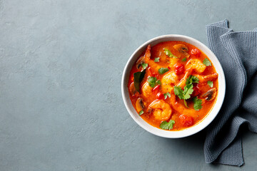 Soup Tom Yum with prawns in a bowl. Grey background. Copy space. Top view.