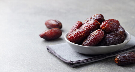 Fresh medjool dates in bowl. Grey background. Copy space. Close up.