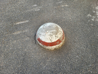 An old white hemisphere with a red stripe, concrete anti-parking.