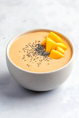 Creamy mango smoothie bowl topped with chia seeds and fresh mango slices