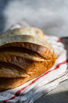 Close-up of a loaf of freshly sliced homemade white bread on a tea towel in sunlight