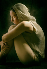 Woman with golden hood sitting and looking over her arms resting on her legs 3