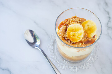homemade no-bake banoffee pie in a glass cups on white table.