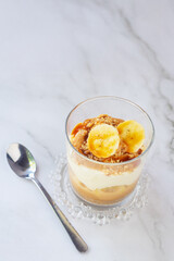 homemade no-bake banoffee pie in a glass cups on white table.