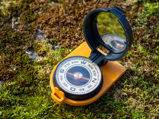 Vintage multifunctional compass on moss background. The easiest way to check direction. Traveler...