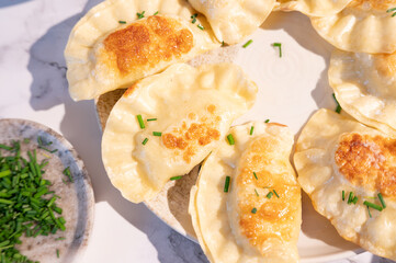 Close-up of fried dumplings on a plate sprinkled with freshly chopped green onions.