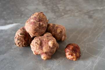 Organic Jerusalem artichoke tubers resting on a polished marble background.