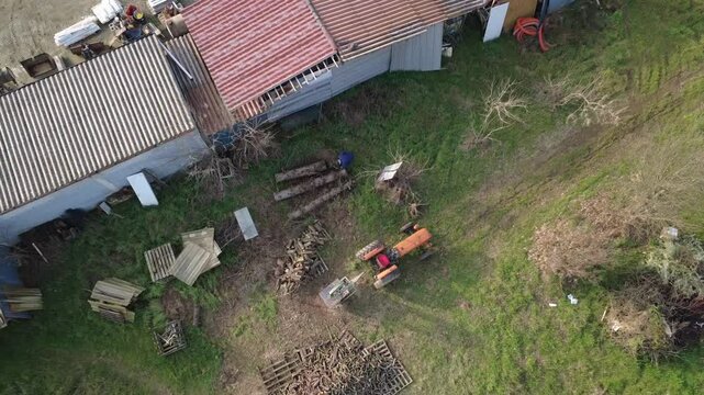 Tagliare la legna in campagna con trattore e taglialegna circolare,  Alessandria, Piemonte, Italia