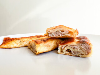 Folded and stuffed pancakes lie on a wooden board in the kitchen
