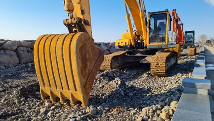 Yellow excavator among rocks at a work site