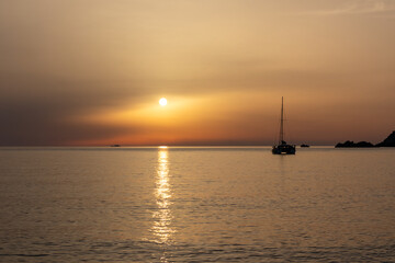 Sunset at the sea with a sailboat. Sardinia, Rena Majori beach.