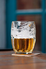 Refreshing golden beer with foam in a glass on a wooden table, creating a cozy pub atmosphere