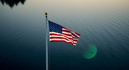 Fototapeta premium American Flag Waves Proudly Against a Serene Water Backdrop Reflecting Patriotism