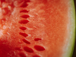 A close-up of a watermelon cut in half, with bright red flesh, green skin, and a fibrous texture....