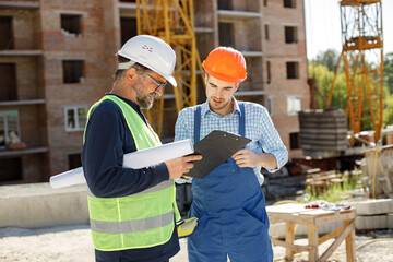 Two men engineers at a construction site are looking at the drawings