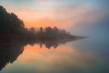 Obraz premium Sunrise over a tranquil lake in Sweden with fog and reflections