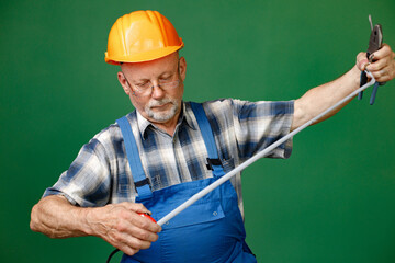 Studio photo of a man worker holding roulette isolated on green background