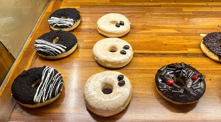 Display of delicious pastries with assorted glazed donuts in shop counter. Donut chocolate sprinkle, blackforest, creme tiramisu, oreo cookies and crumb