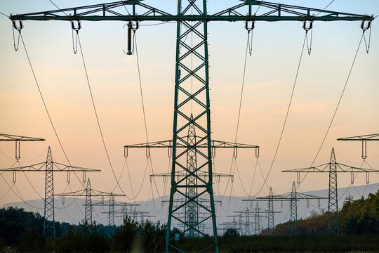 High voltage power lines over a field at sunset