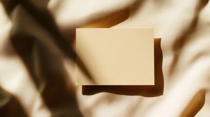 Fototapeta premium Beige Notecard on Draped Fabric with Sunlight Shadows