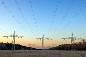 High voltage power lines over a field at sunset