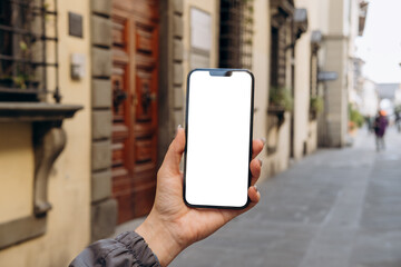 Mockup woman's hand holding using smart phone with white blank screen POV at on the background of a...