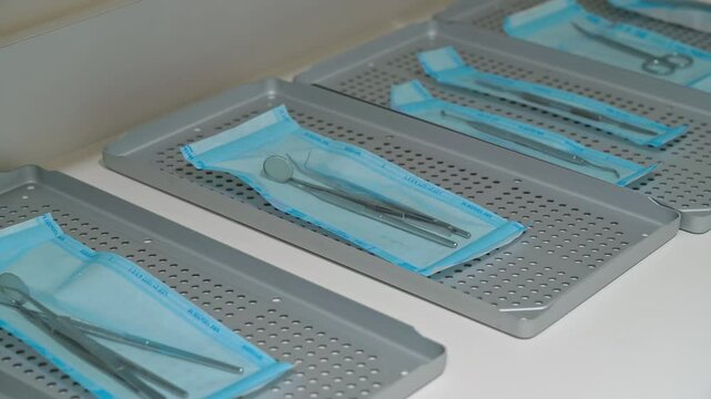 Sterilized dental instruments sealed in blue medical pouches placed on perforated metal trays in clean organized clinical environment ensuring hygiene and safety in modern dental practice