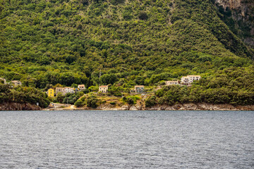 Beautiful, small houses on Cres island shore at the village of Merag, Croatia, hidden by the forest covered slopes