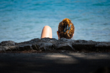 Young woman photographed on the Cres island beach, Croatia,  while reading book and sunbathing at the same time