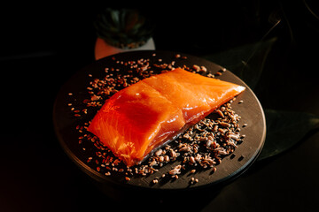 Fresh organic trout fillet ready for cooking on a black board with spices in preparation for a delicious meal