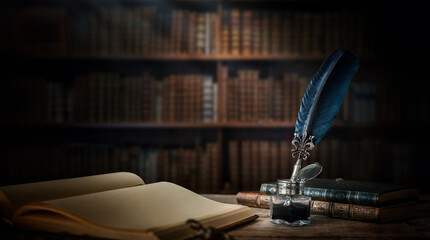 Old quill pen with an inkwell, papers and books on a table against an old bookshelf. Concept on the...