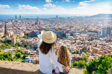 A tourist monther shows her daughter the panoramic view of the skyline of Barcelona, Spain, on a sunny day