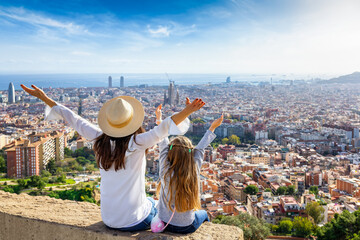 A happy tourist mother and her daughter looking at the skyline of Barcelona, Spain, during a sunny...
