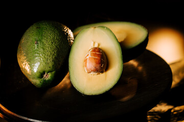 Fresh avocado halves displaying rich green flesh and a prominent seed on a dark surface