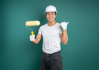 Painter with roller pointing to blank space on a blue-green wall. Perfect for promoting products or...