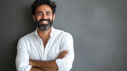Obraz premium Handsome mid adult man with beard and crossed arms looking at camera. Mature middle eastern man isolated against grey wall and smiling. Satisfied indian guy looking at camera with a big laugh.