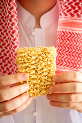 Obraz premium Saudi in Arab dress holding out instant noodles