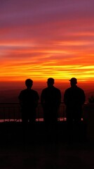 Obraz premium Three men stand on a balcony looking out at the sunset