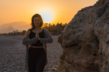 Woman hands place together like praying in front of nature blur beach sunset sky
