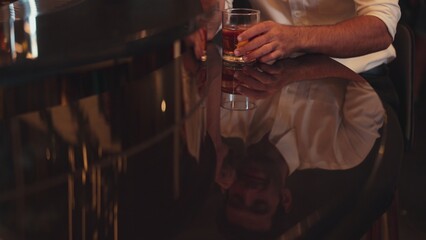 Smart man in white shirt drinking cocktail Old fashioned while calling on smartphone mirror counter bar reflect shooting in special party beverage vibrant nightclub on Friday meeting night. Vinosity.
